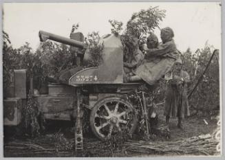 [soldiers in gas masks sitting at a gun]