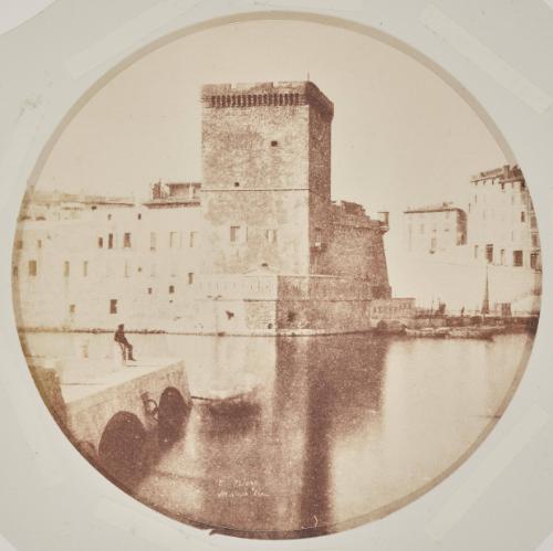 View of the tour du roi René in the Port of Marseille. A man sits on a bollard  to the left.