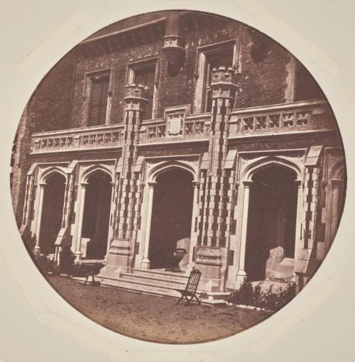 View of an entrance on the façade of the Château de Vallombrosa, Cannes. Two folding wooden chairs are placed on the terrace in front of the doorway and one in the centre of the doorway