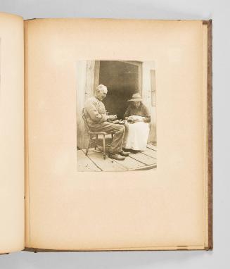 [A woman looks at a small book while a man cradles a bowl in his lap] Page 35 of The Abenaki; from collection of Canadian albums compiled by Edith S. Watson, 1890s-1930s
