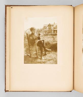 [Child sits in a rocking chair outside, with sweetgrass in their lap.] Page 18 of The Abenaki; from collection of Canadian albums compiled by Edith S. Watson, 1890s-1930s