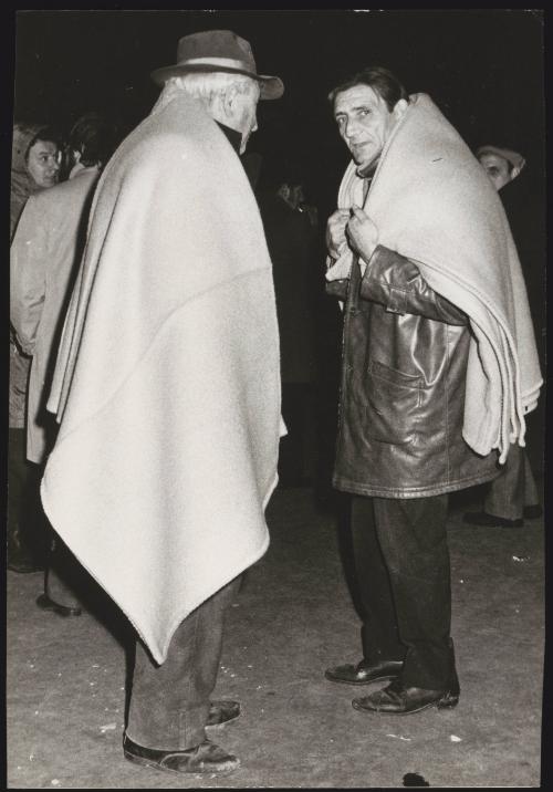 Two men wrap themselves in blankets on the street in the aftermath of an earthquake in Tuscany that left about 5,000 homeless