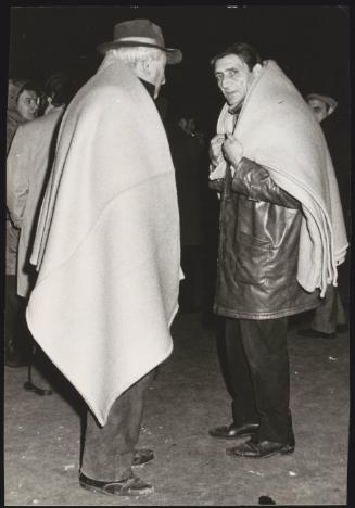 Two men wrap themselves in blankets on the street in the aftermath of an earthquake in Tuscany that left about 5,000 homeless