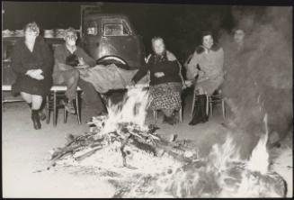Neighbours and family sit around a fire in a refugee camp in the aftermath of an earthquake in Tuscany that left about 5,000 homeless