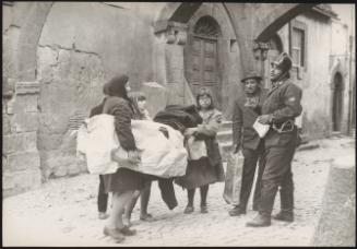 A policeman talks to a family clutching their belongings in the aftermath of an earthquake in Tuscany that left about 5,000 homeless
