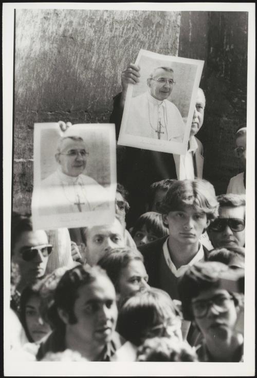 Pictures of Pope John Paul I are held up by people in the crowd waiting to view his body lying in state at St. Peter's basilica, 29 September 1978