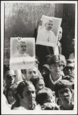Pictures of Pope John Paul I are held up by people in the crowd waiting to view his body lying in state at St. Peter's basilica, 29 September 1978