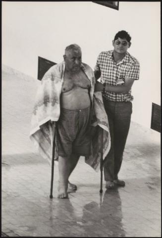 A  freshly baptised Jehovah's Witnesses on crutches is led away from the swimming pool, Genova