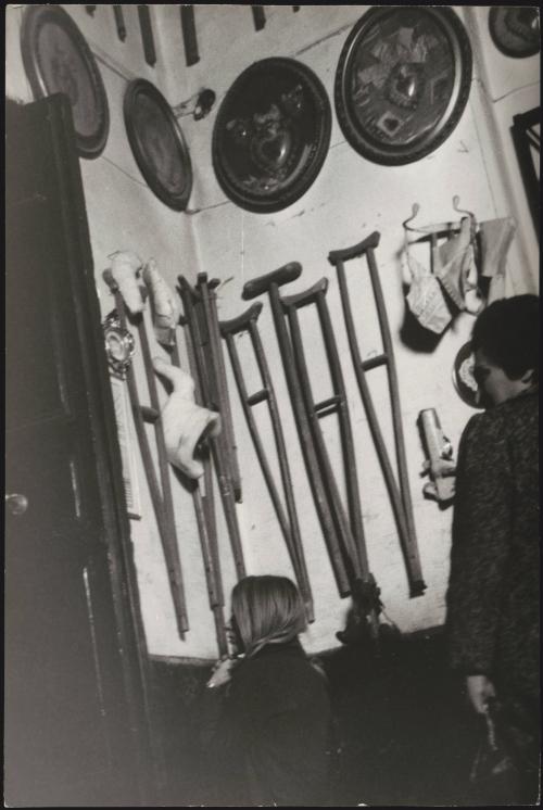 A young woman kneels in prayer in front of votive crutches