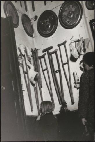 A young woman kneels in prayer in front of votive crutches