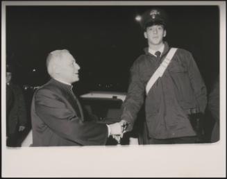 Cardinal Poletti shaking the hand of a policeman