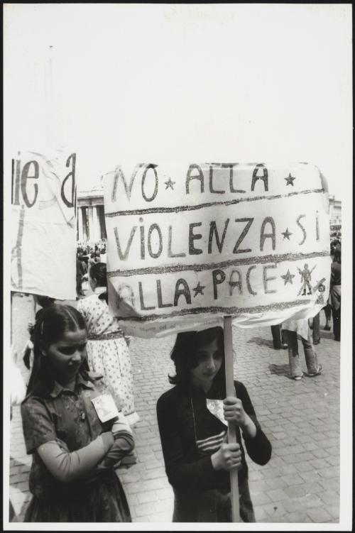 Two young girls in St. Peter's Square, one holding a banner that reads "No to Violence, Yes to Peace"