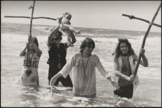 Young, religious hippies waist-deep in the sea, carrying out a baptism