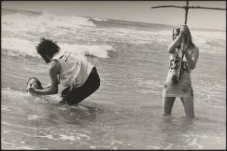 Religious hippies carry out a baptism in the sea