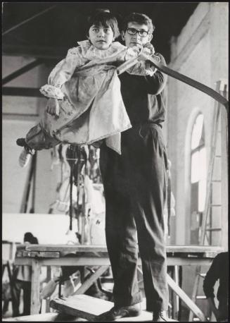Children being prepared for a religious procession, dressed as angels and suspended on structures to appear as though they are flying