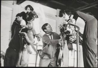 Children being prepared for a religious procession, dressed as angels and suspended on structures to appear as though they are flying