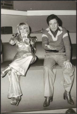 Actor Ugo Pagliai and personality Raffaella Carrà   sit together in an unspecified green room. 