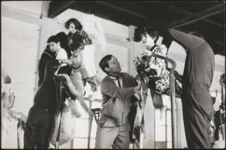 Children being prepared for a religious procession, dressed as angels and suspended on structures to appear as though they are flying