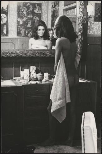 A nude Florinda Bolkan stands in front of a bathroom mirror