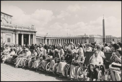 A religious congregation gather in St. Peter's Square, a line of people in wheelchairs at the front of the crowd