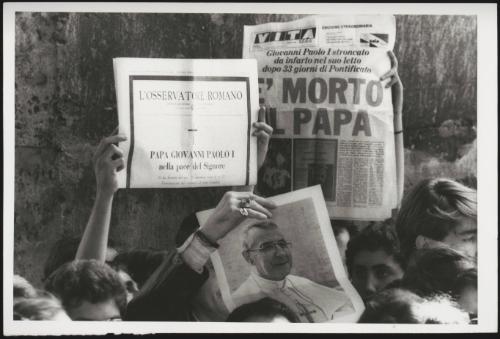 Members of the public hold up newspaper clippings headlining the death of Pope John Paul I