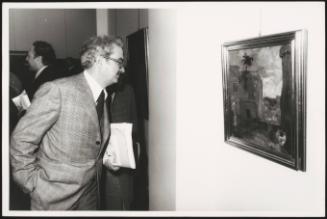 Emanuele Macaluso of the PCI inspects a painting at a gallery