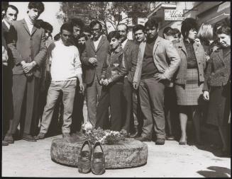 A group of people grieve at a makeshift shrine made from a tyre, flowers and a pair of shoes, in Battipaglia, 1969
