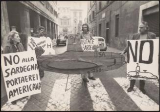 Demonstrators against aircraft carriers off the coast of Sardinia holding a handmade submarine cut-out