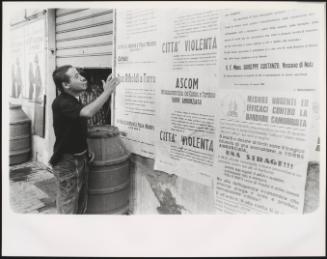 A man reads protest posters plastered to a wall