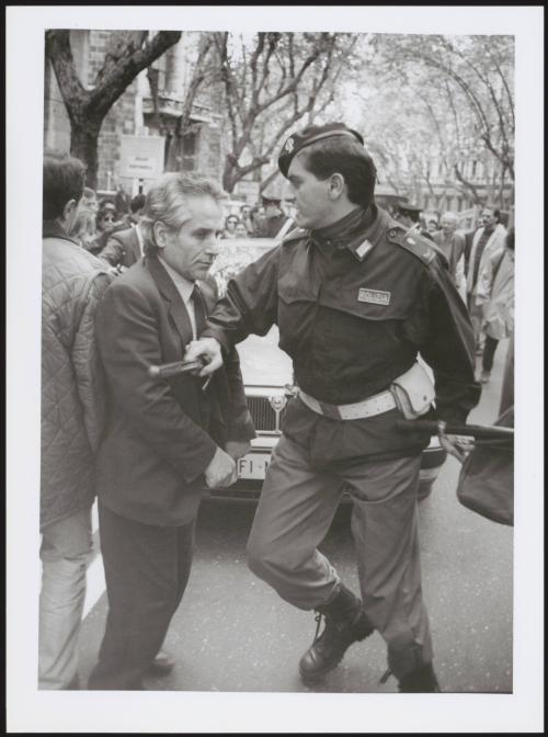 A riot policeman pushes a man back with his baton