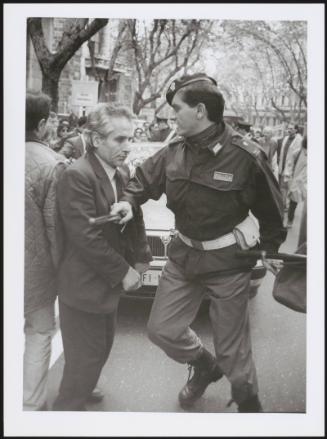 A riot policeman pushes a man back with his baton