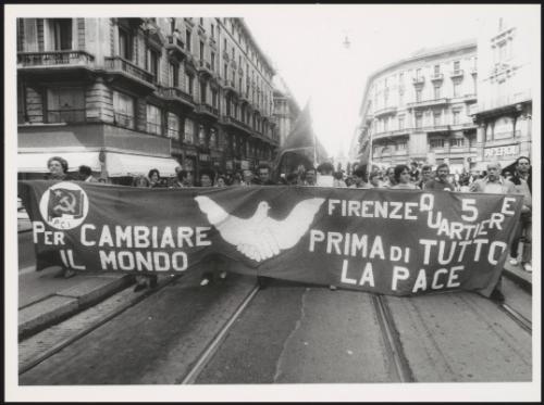 Milan 1982. A crowd of protesters march behind a large banner from the Florence quarter of the P.C.I, down a street at a communist  peace march 