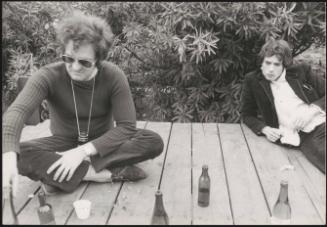 Bernardo Bertolucci and Pierre Clementi sit on a deck drinking beers