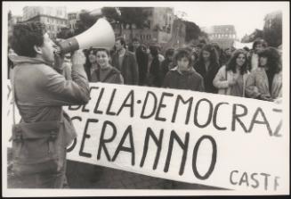 A man talks to a crowd of protesters through a megaphone
