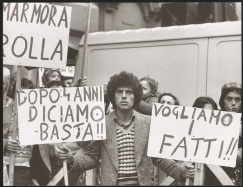 A man at a protest holds two placards

