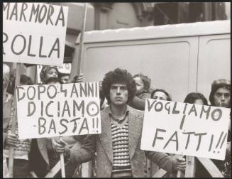 A man at a protest holds two placards
