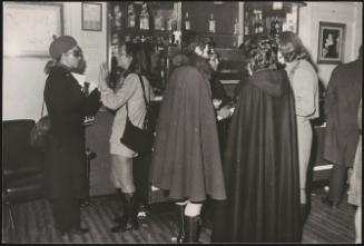 Women in winter coats talk at a bar