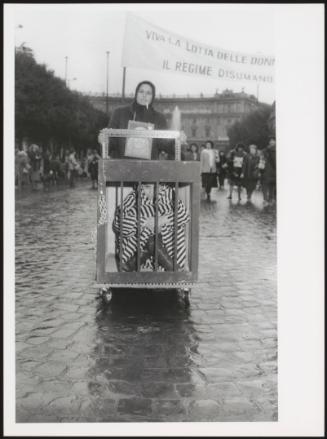A demonstration for women's rights; a woman pushes another woman locked in a cage