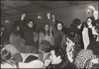 Women march through a crowded room, during a feminist protest in Rome, 1971