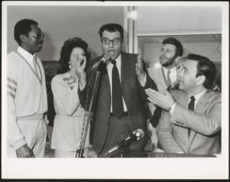 Pietro Longo and a group stand around a microphone in a studio