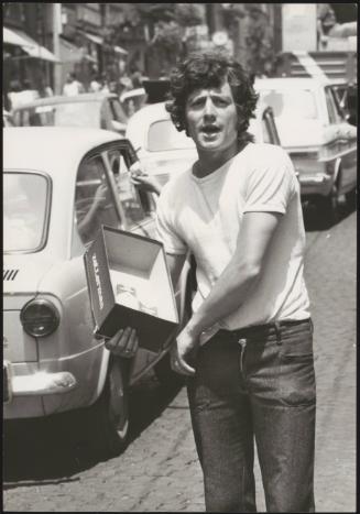 A man selling contraband cigarettes from a shoe box