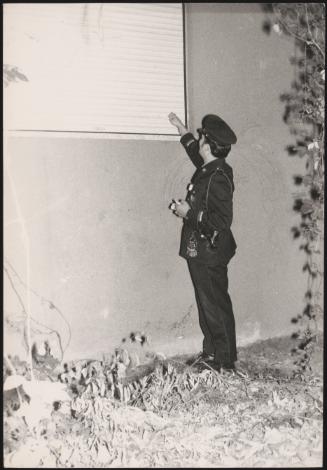 A police officer checks on a closed up window