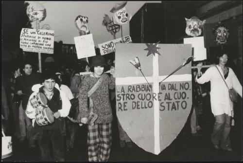 A demonstration against Police brutality; the Indiani Metropolitani carry placards, bongos and grotesque papier maché heads on sticks
