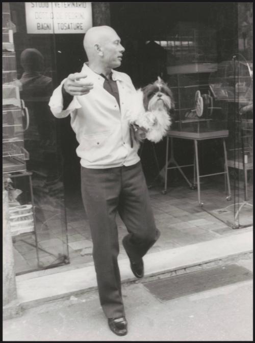 Actor Yul Brynner leaving a pet shop with a dog in his arms