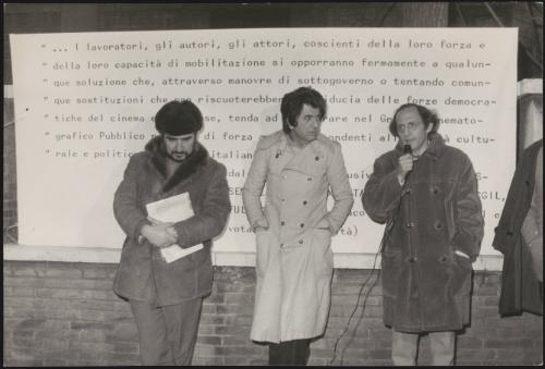 Citto Maselli, Nanni Loy and Pietro Buttitta all writers and directors, take a stand with a microphone in front of a written manifesto, protesting against Italian politics interfering with film production and workforce
