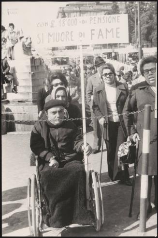 A man in a wheelchair at a protest for the disabled 
