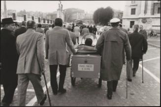 Men who were injured in the Great War march with walking sticks down the street with a motorized wheelchair as part of a protest for the disabled