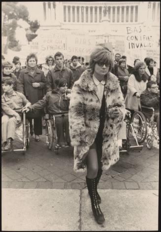 A woman in long boots and a fur coat leading a protest for the disabled