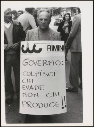 At a farmer's demonstration a man wears a protest placard
