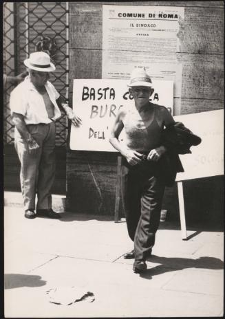 Two demonstrators in Rome, stand by a hand painted placard.